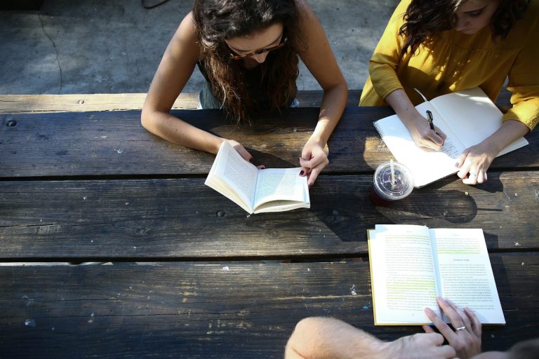 Students working on homework/coursework in a study group on a bench