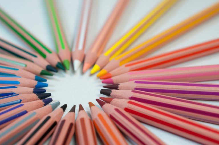 A series of multicoloured drawing pencils arranged in a circle, facing inwards